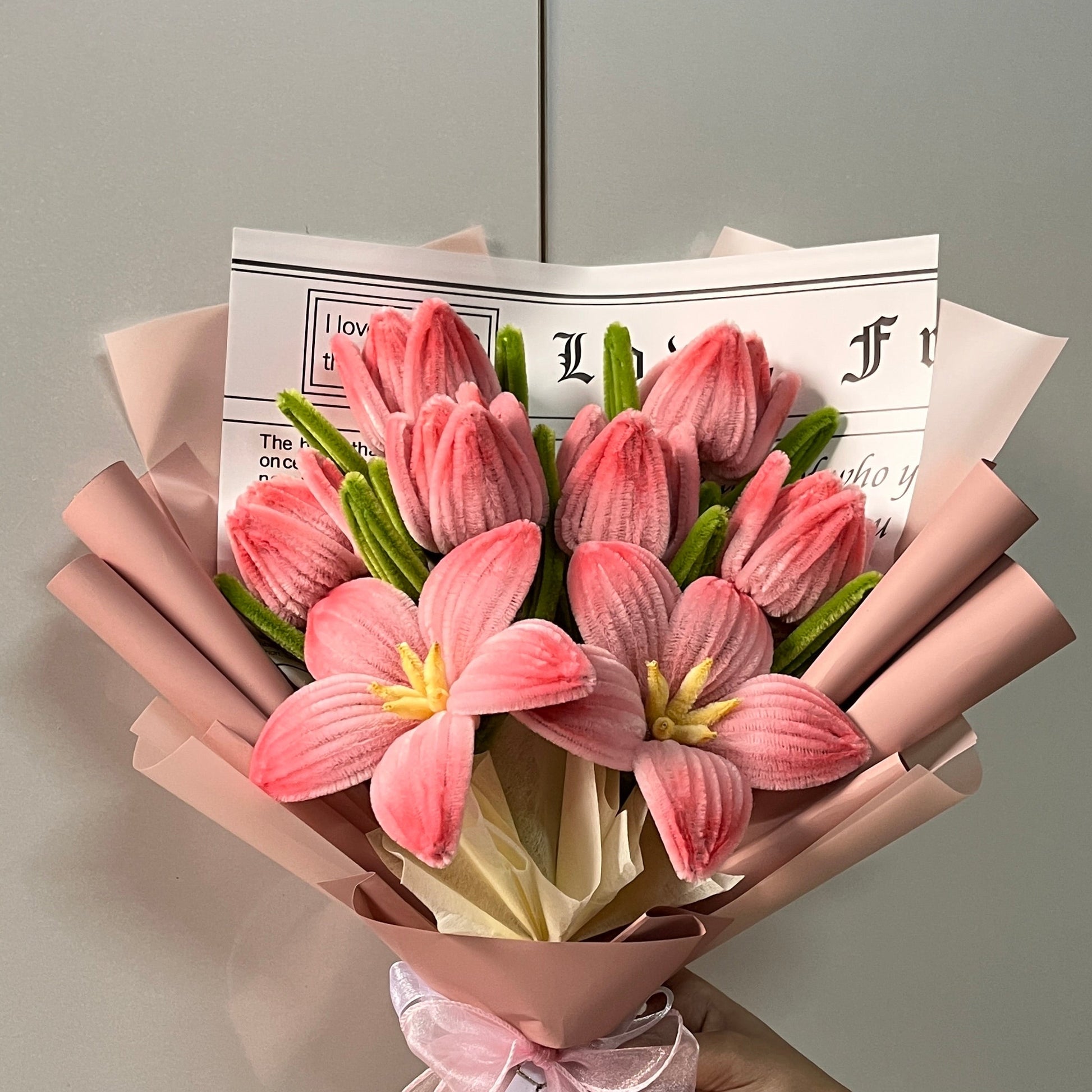 Bouquet of peach pink tulips made with high quality pipe cleaners, aesthetically wrapped held against a light gray background.
