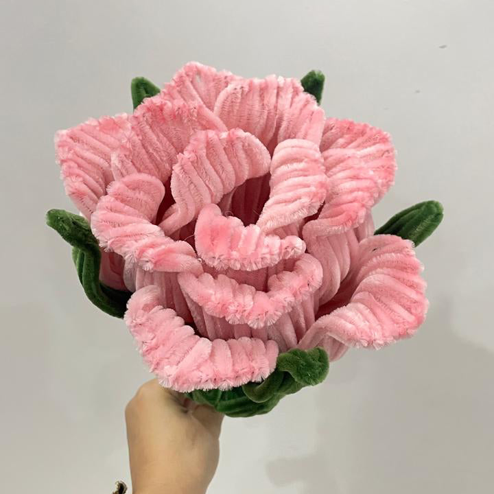 Peach pink rose flower made using pipe cleaners held by a hand against a white background